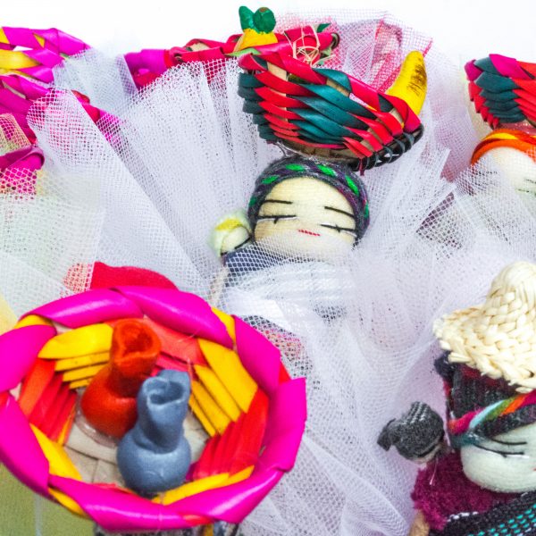 bomboniere cresima con confetti in sacchetti di tulle colorati e decorati con bamboline abbellite con cesti in testa vivaci e differenziati provenienti dal Guatemala con calamita sul retro.