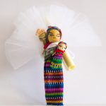 bomboniere cresima con confetti in sacchetti di tulle colorati e bamboline con bimbo sulle spalle e oggetti tradizionali provenienti dal Guatemala con calamita sul retro e pergamena.